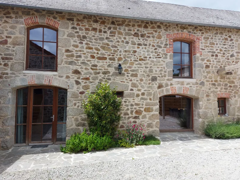Cour intérieure en pierre du gîte avec fenêtres à encadrements de brique