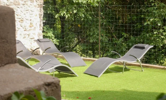 Jardin en contrebas avec transats sur pelouse, entouré de verdure