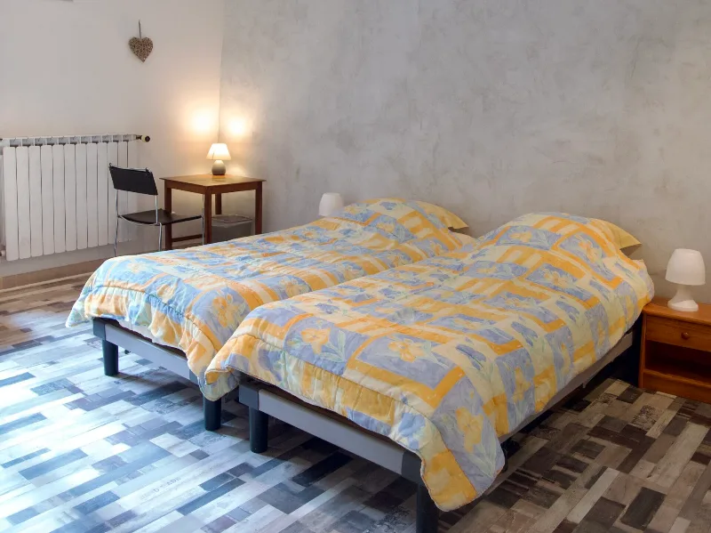 Chambre avec deux lits simples, radiateur et fenêtre sur la ruelle