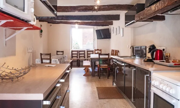Cuisine équipée avec grande table à manger en bois et poutres apparentes