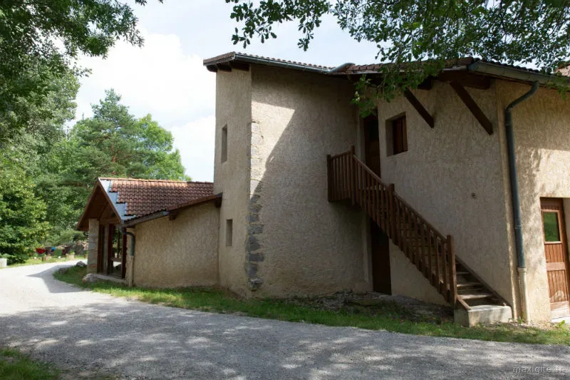 Façade en pierre du gîte avec escalier extérieur en bois menant à l'étage