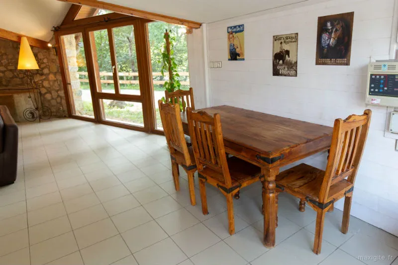 Salle à manger véranda avec grande table en bois et baies vitrées sur le jardin