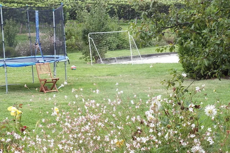 Coin balançoires et jeux extérieurs pour enfants au fond du jardin fleuri