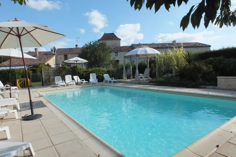 Piscine extérieure entourée d'une terrasse ombragée avec vue sur les collines