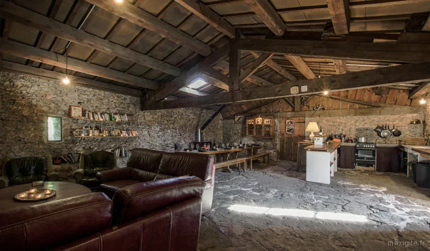 Coin cuisine et salon avec poutres apparentes, sous les toits de la maison forestière