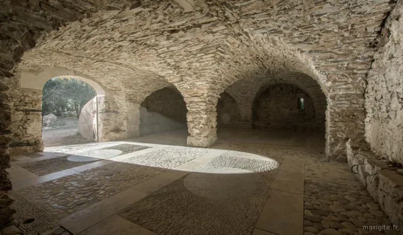 Grande salle voûtée en pierre de 80 m² avec sol en galets, espace de vie principal