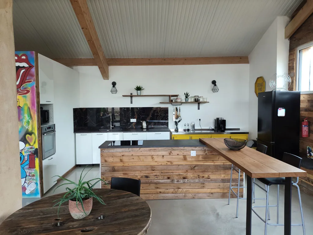 Cuisine ouverte entièrement équipée avec îlot central en bois et bar pour repas conviviaux