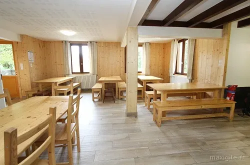 Grande salle à manger commune avec longues tables en bois pour les repas de groupe