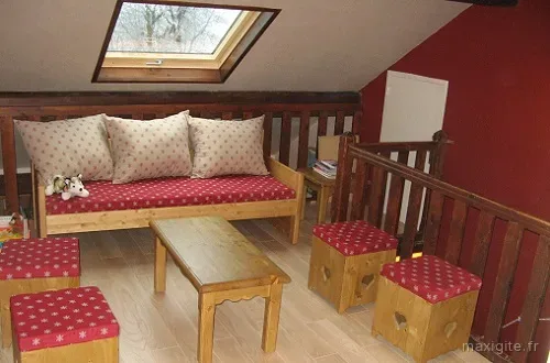 Coin salon en mezzanine sous les combles avec banquettes rouges et lucarne