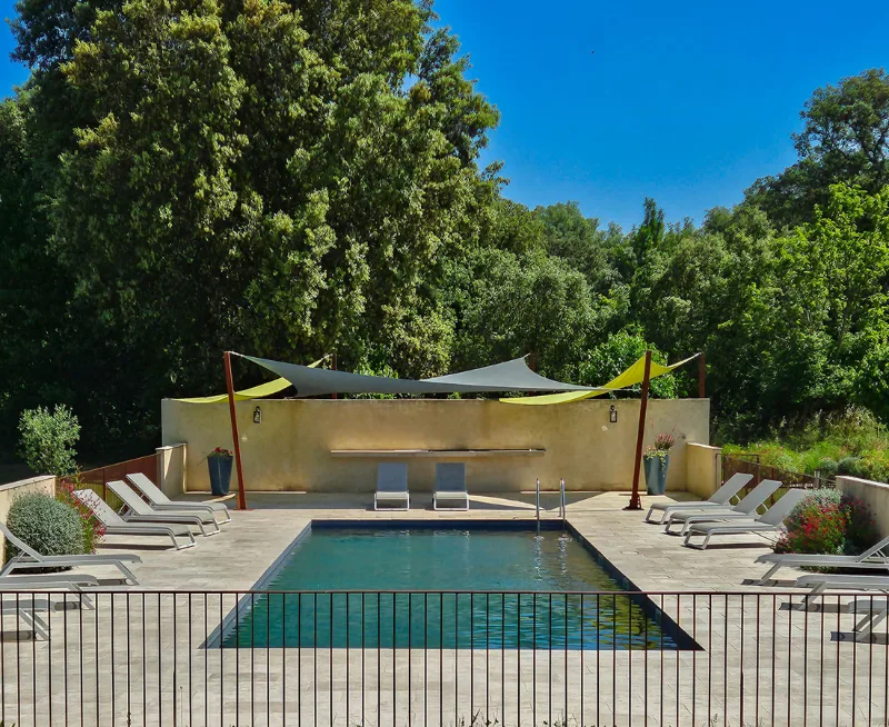 Piscine du domaine avec plage engazonnée et transats au soleil