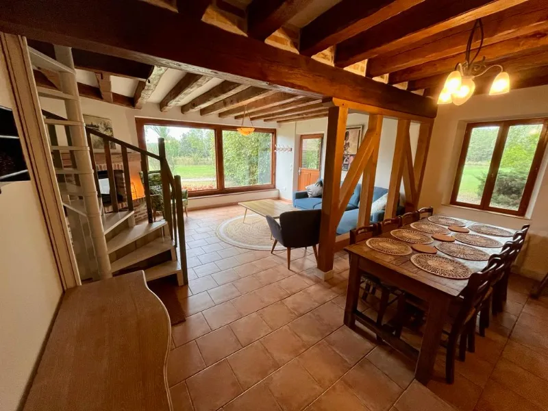 Séjour avec poutres apparentes en chêne, grande table à manger et vue sur le parc