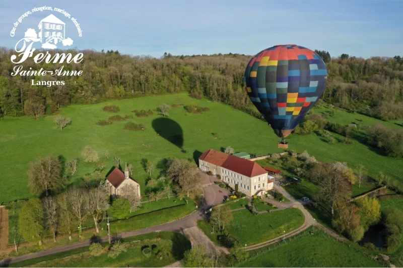 Vue aérienne du domaine de la Ferme Sainte-Anne à Langres, chapelle et bâtisse en pierre au milieu des prés
