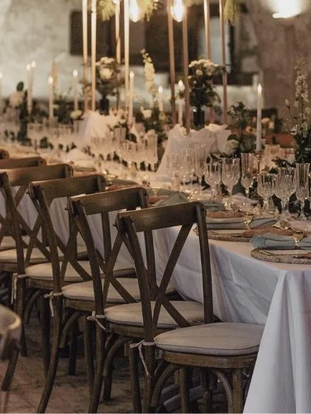 Salle de réception dressée pour un dîner de mariage avec longues tables, chandeliers et fleurs