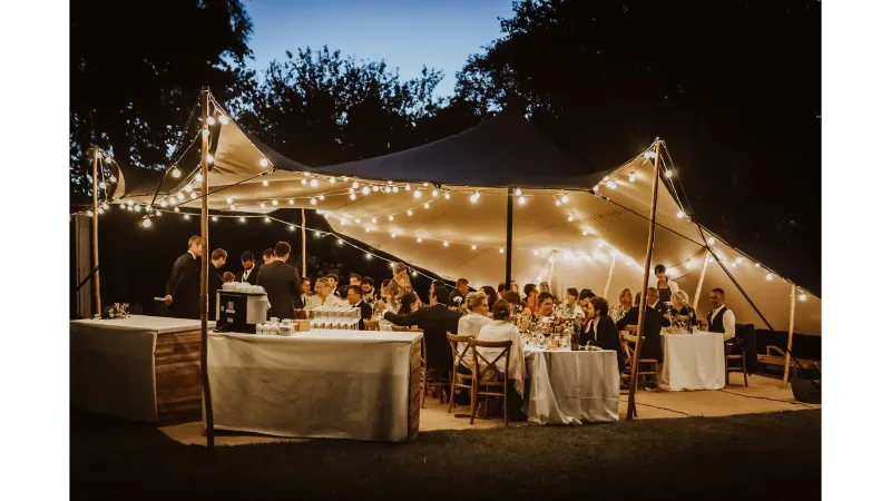 Tente nomade en soirée avec guirlandes lumineuses et tables dressées pour un événement festif