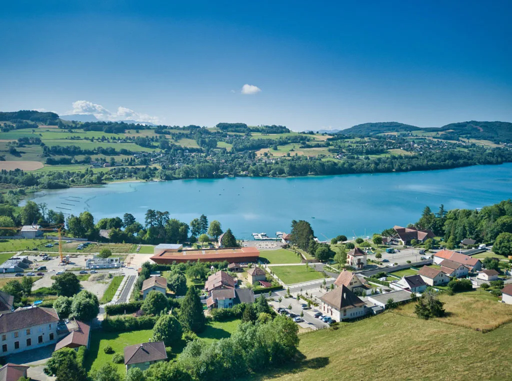 Gîte de groupe Centre Bellevue à Paladru — Vue aérienne du lac de Paladru avec le village et le Centre Bellevue en contrebas, entouré de verdure, capacité 60 personnes