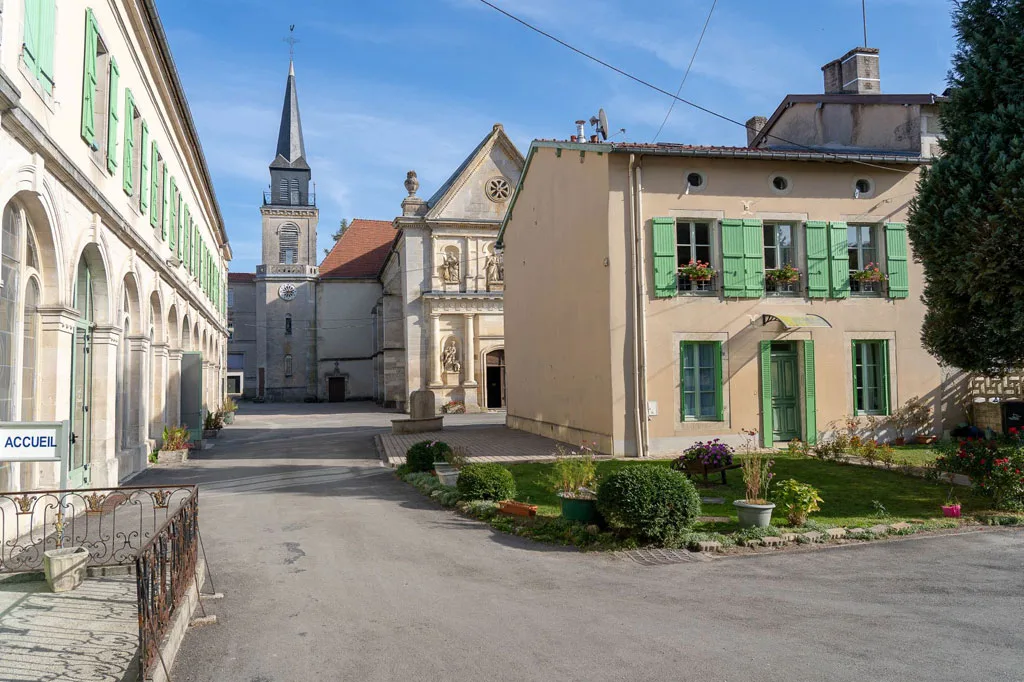 Gîte de groupe Centre d'Accueil de Benoîte-Vaux à Rambluzin et Benoîte-Vaux — Cour principale du Centre d'Accueil de Benoîte-Vaux avec bâtiments historiques, église et jardin verdoyant, capacité 99 personnes