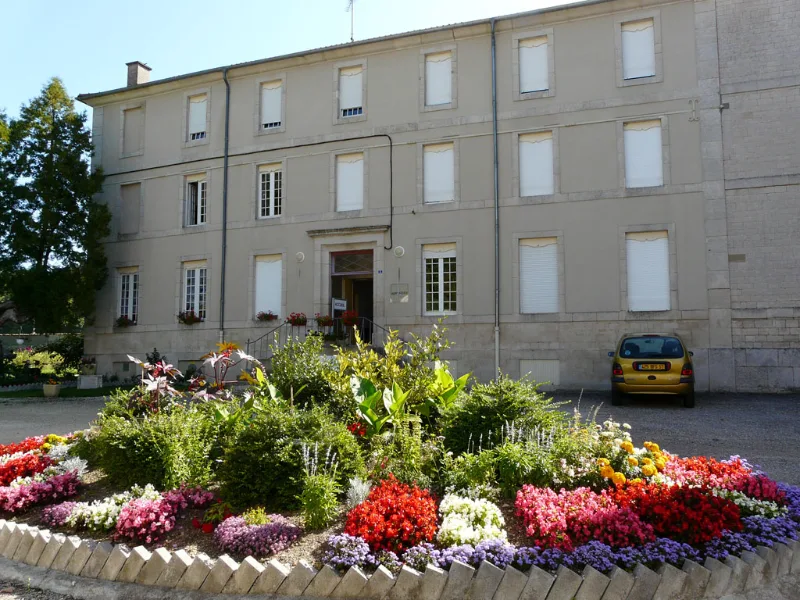 Façade fleurie du bâtiment Le Monastère avec massif de fleurs colorées en été