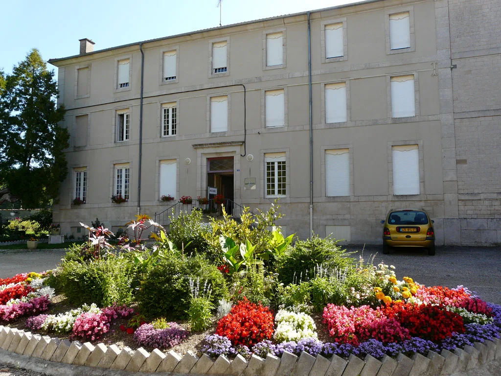 Façade fleurie du bâtiment Le Monastère avec massif de fleurs colorées en été