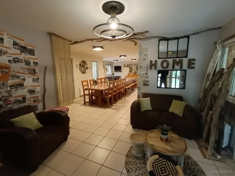Grand séjour avec longue table à manger en bois, coin salon et décoration artistique originale