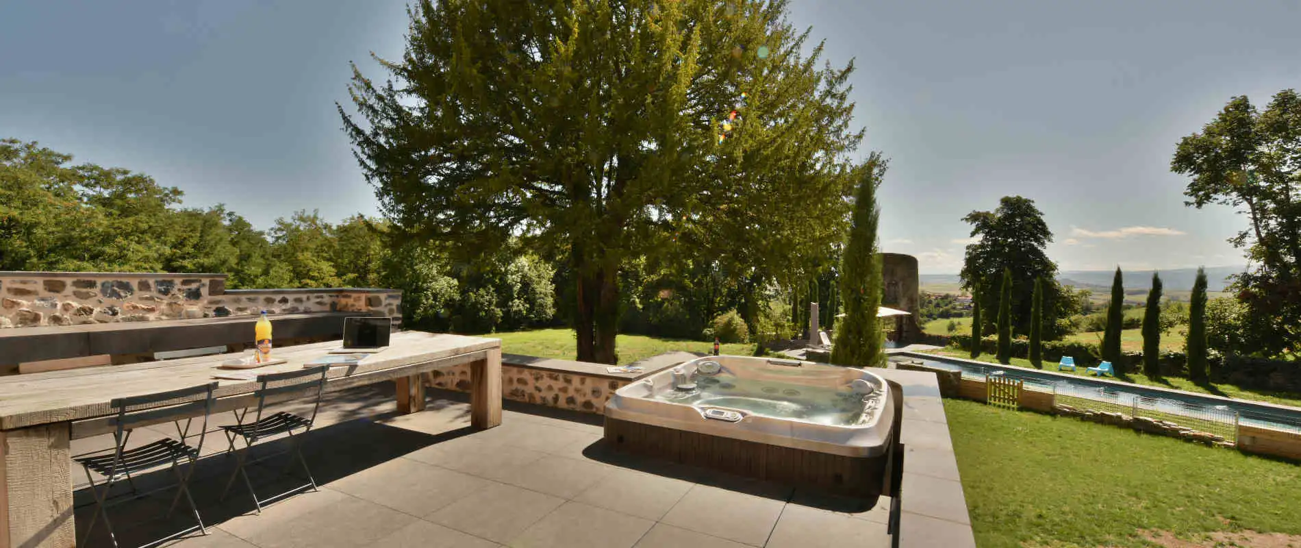 Terrasse extérieure avec jacuzzi et vue dégagée sur la campagne du Puy-de-Dôme