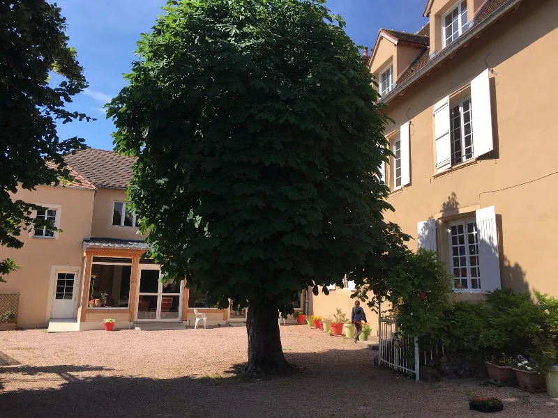 Cour intérieure arborée du Manoir La Grand'Cour au printemps, avec vue sur les bâtiments