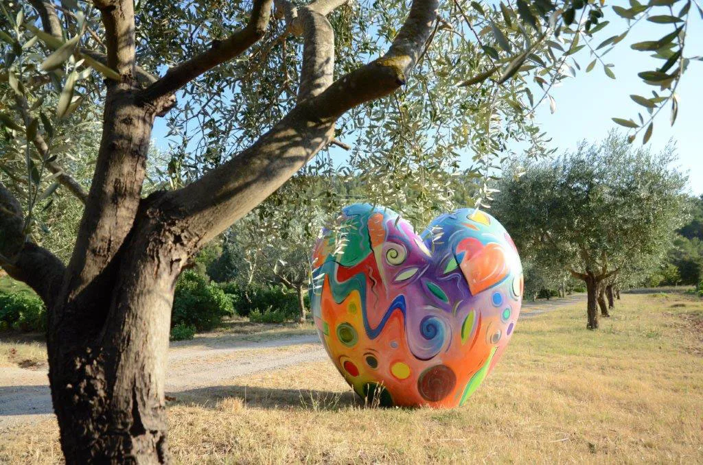 Gîte de groupe Domaine Hemmitage à Salernes — Vue du parc du Domaine Hemmitage avec sculpture artistique colorée et allée d'oliviers, capacité 30 personnes