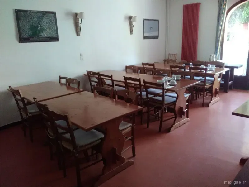 Réfectoire du centre avec tables et chaises alignées, carrelage rouge et lumière naturelle