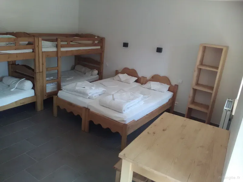 Chambre avec lits superposés en bois, lit simple et table en pin