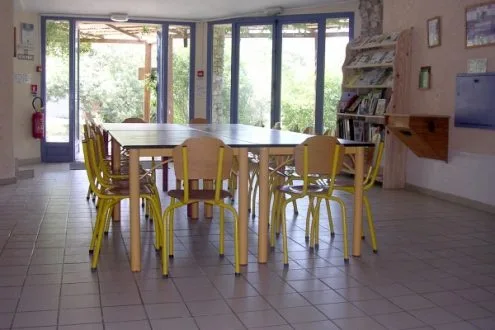 Grande salle commune de 52 m² avec tables et chaises pour les repas de groupe