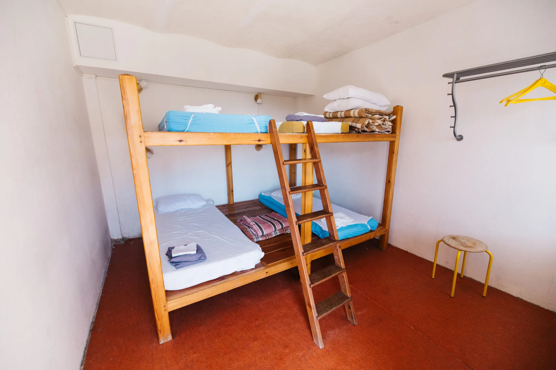 Chambre refuge avec lits superposes en bois et echelle dans ambiance montagnarde