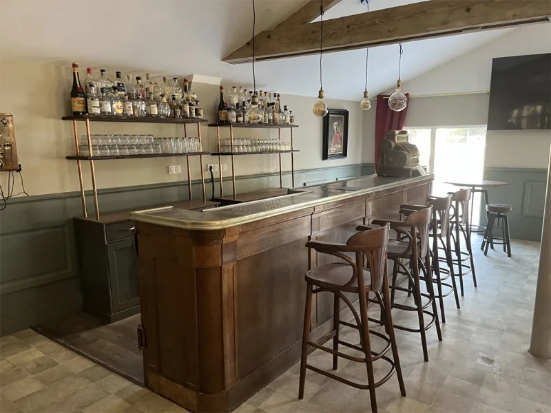 Bar en bois massif avec étagères de bouteilles et tabourets bistrot
