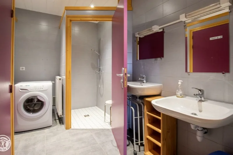 Salle de bain avec douche a l italienne, lave-linge, deux lavabos blancs sur meuble bois et murs roses et gris