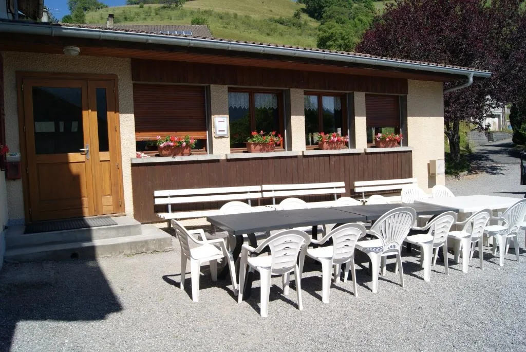 Gîte de groupe Les Hermones à Vailly — Facade du gite Les Hermones avec terrasse couverte, mobilier de jardin et montagne boisee en arriere-plan, capacité 30 personnes