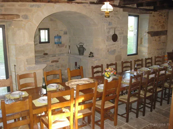Salle à manger spacieuse avec grande table en bois et murs en pierre apparente