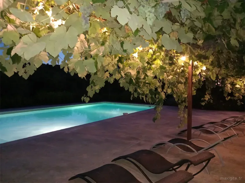 Terrasse ombragée avec mobilier de jardin pour convives et éclairage nocturne