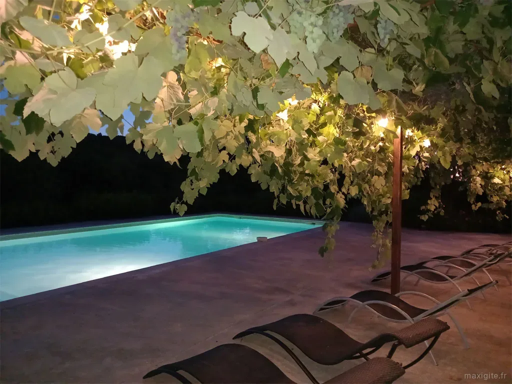 Terrasse ombragée avec mobilier de jardin pour convives et éclairage nocturne