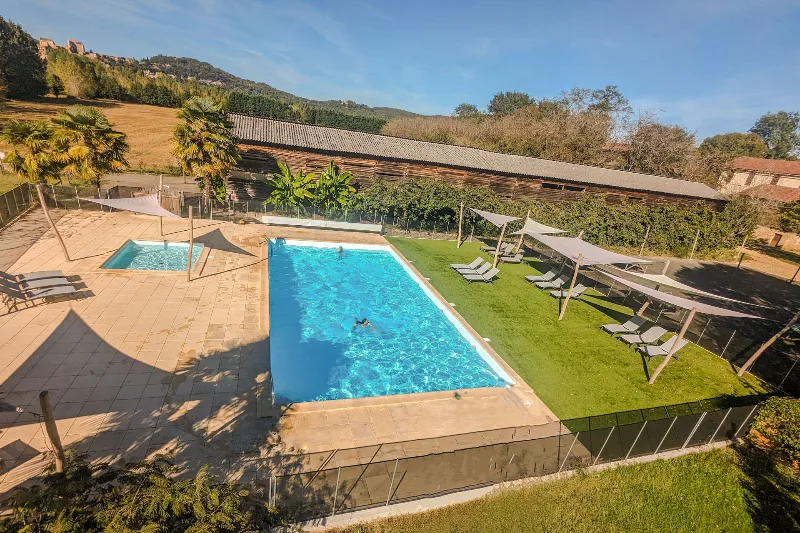 Piscine chauffee avec pataugeoire, transats et voiles d ombrage, vue sur le chateau de Beynac