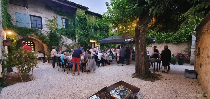 Dîner en soirée dans la cour avec convives attablés sous un barnum éclairé et façade illuminée