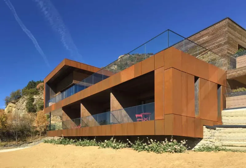 Façade en pierre de la maison La Montagne nichée dans la verdure au pied des collines boisées du domaine