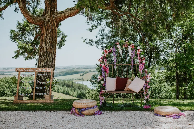 Arche florale de cérémonie sous un grand arbre avec vue panoramique sur la campagne gersoise