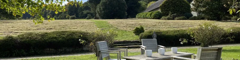 Vaste prairie et terrasse en bois avec statue de Bouddha entourée de rosiers en fleurs