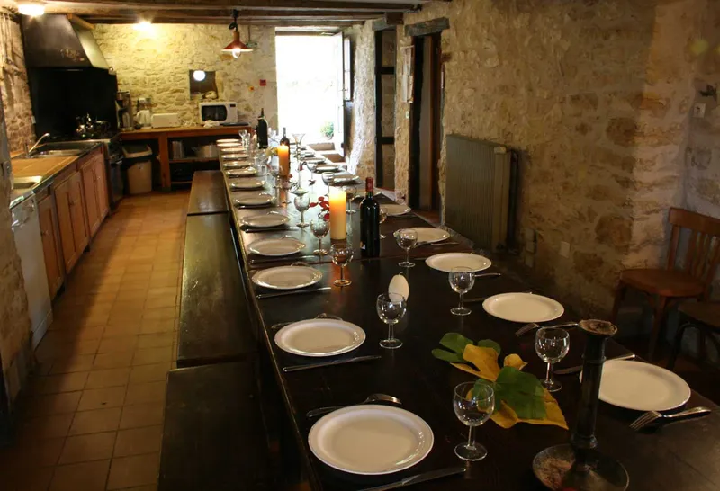Grande salle à manger voûtée en pierre avec longue tablée dressée pour de nombreux convives