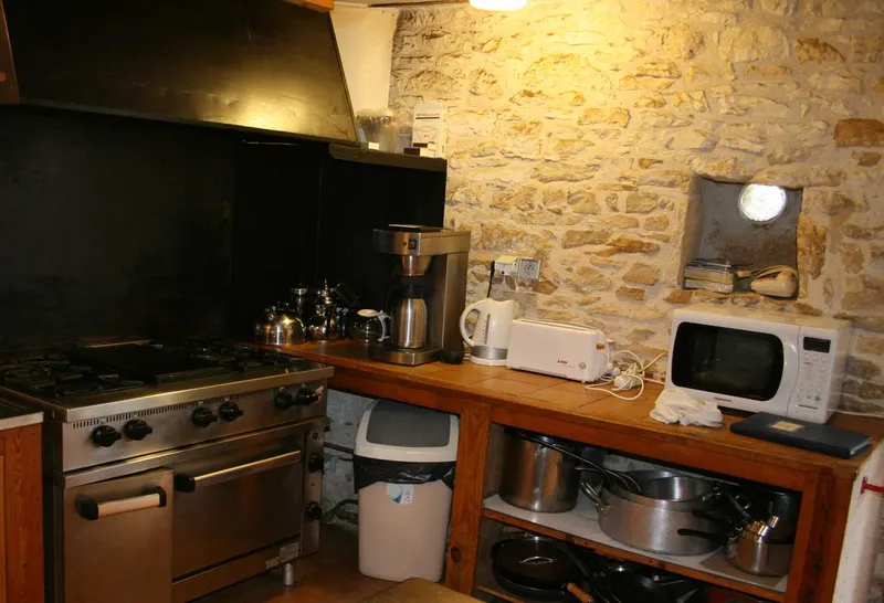 Cuisine professionnelle équipée avec piano de cuisson inox, hotte et four à plusieurs feux