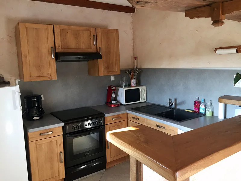 Cuisine équipée en bois avec plaques de cuisson, hotte, four et évier double