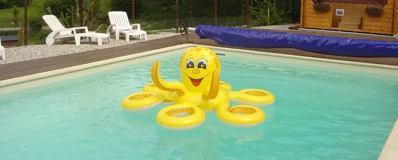 Piscine extérieure bordée de transats blancs, jardin verdoyant et ciel bleu dégagé