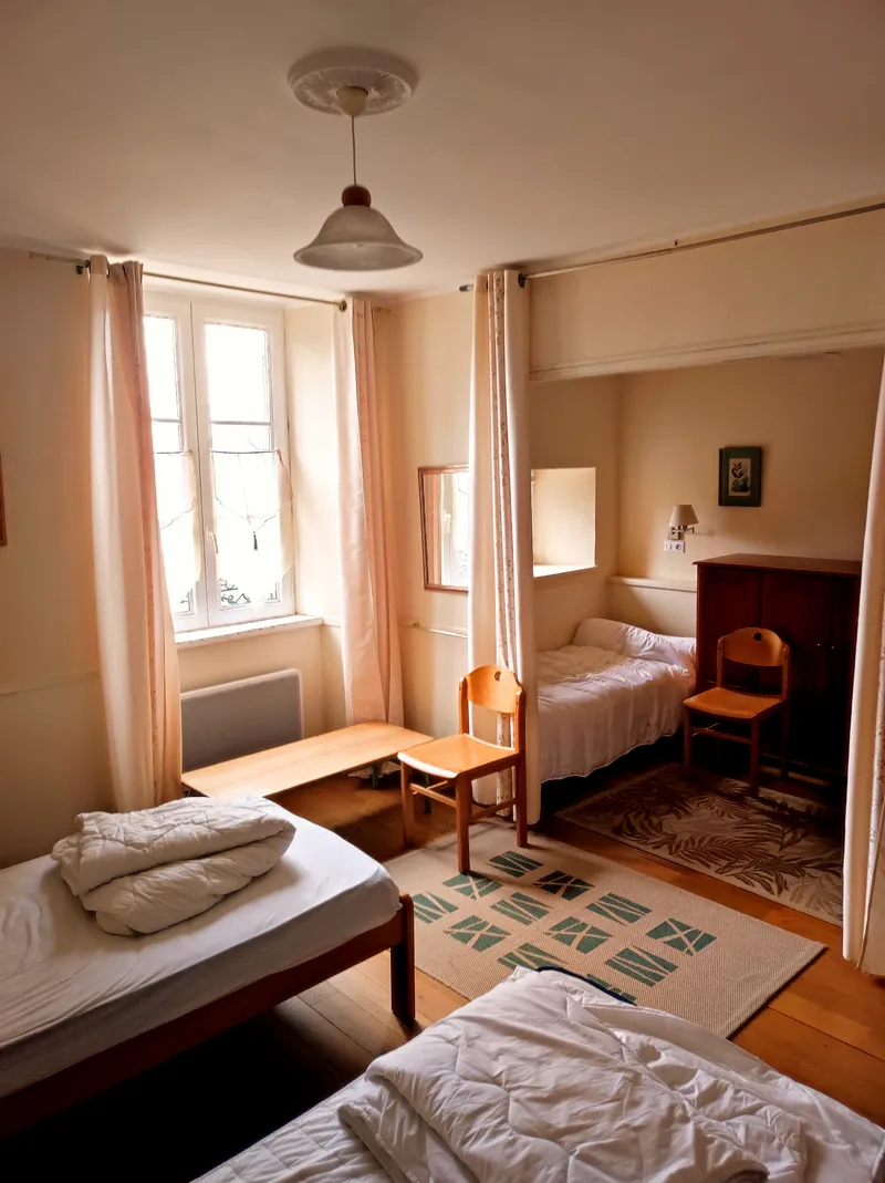 Chambre cosy aux rideaux pêche avec lits simples, commode ancienne et fenêtre lumineuse