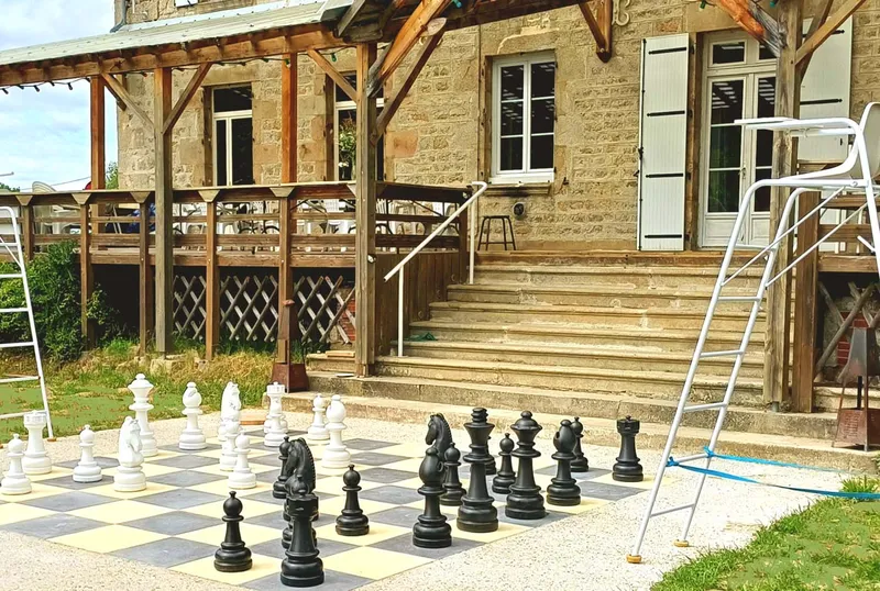 Terrasse extérieure avec jeu d'échecs géant devant la façade en pierre et son escalier