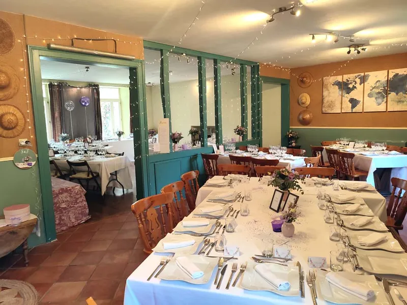 Grande salle à manger dressée pour une réception avec longues tables et guirlandes lumineuses