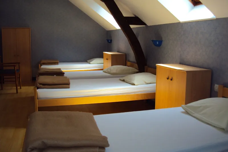 Chambre mansardée avec lit simple, lampe de chevet en bois et fenêtre de toit