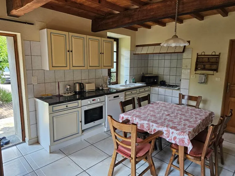 Cuisine équipée aux meubles beiges avec plaque de cuisson, four encastré et grande table à manger